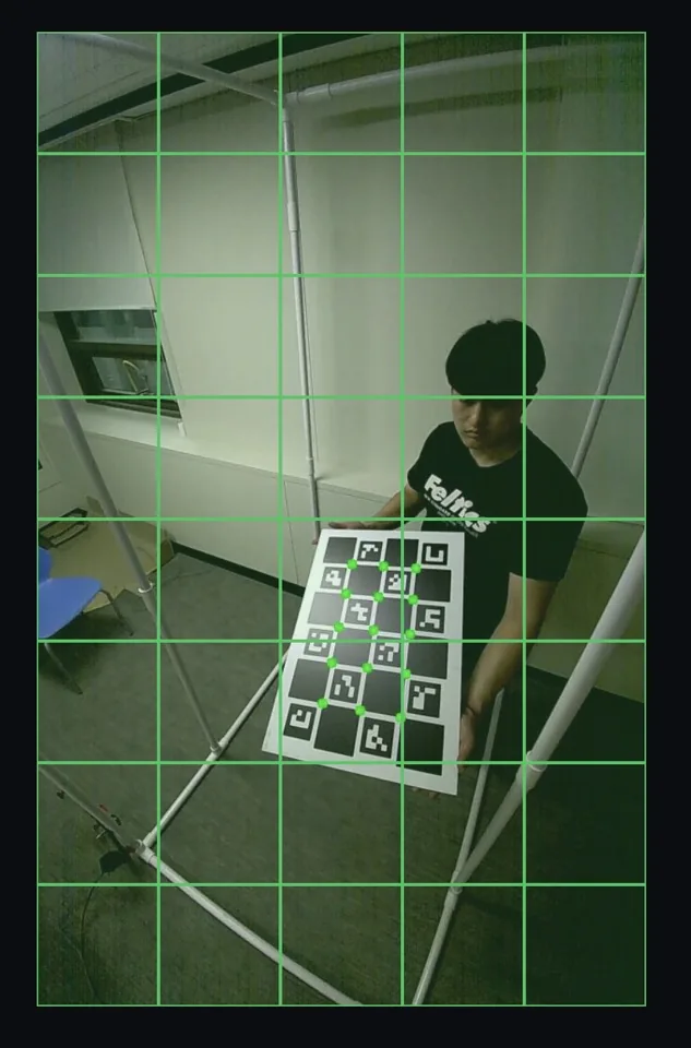 Live camera view in the kiosk with a green grid while a person holds the calibration board