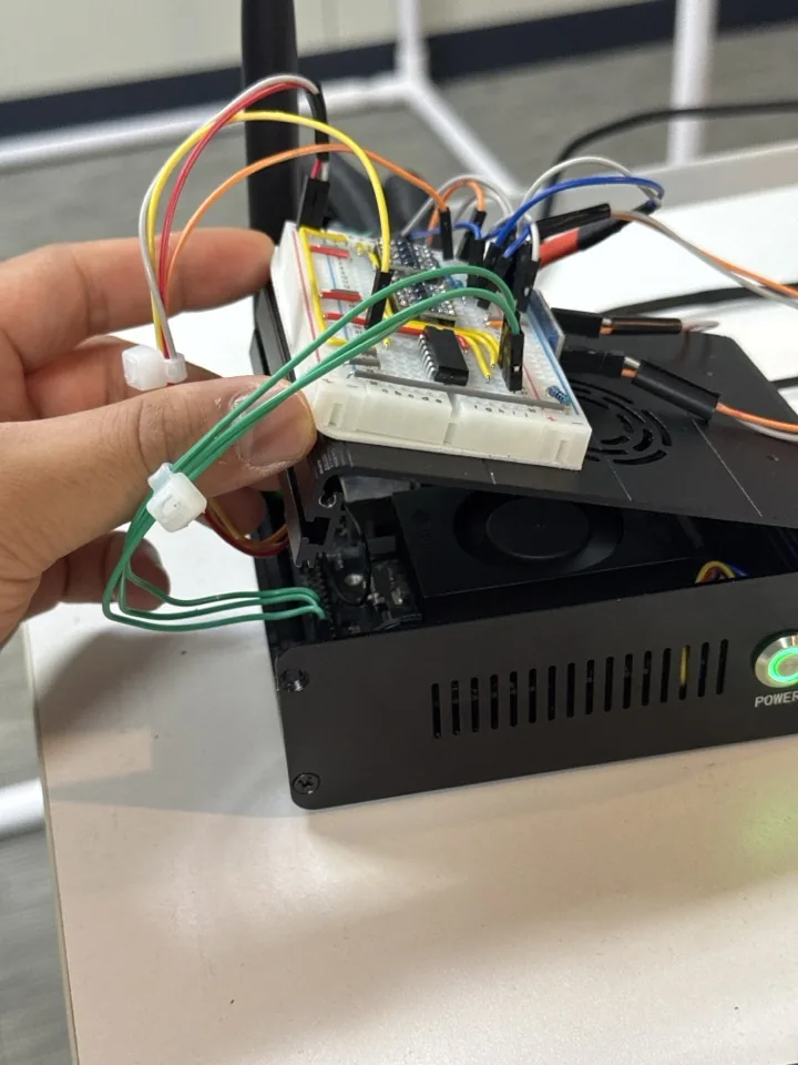 Hand-built trigger board on a breadboard, held over the Jetson with its jumper wires